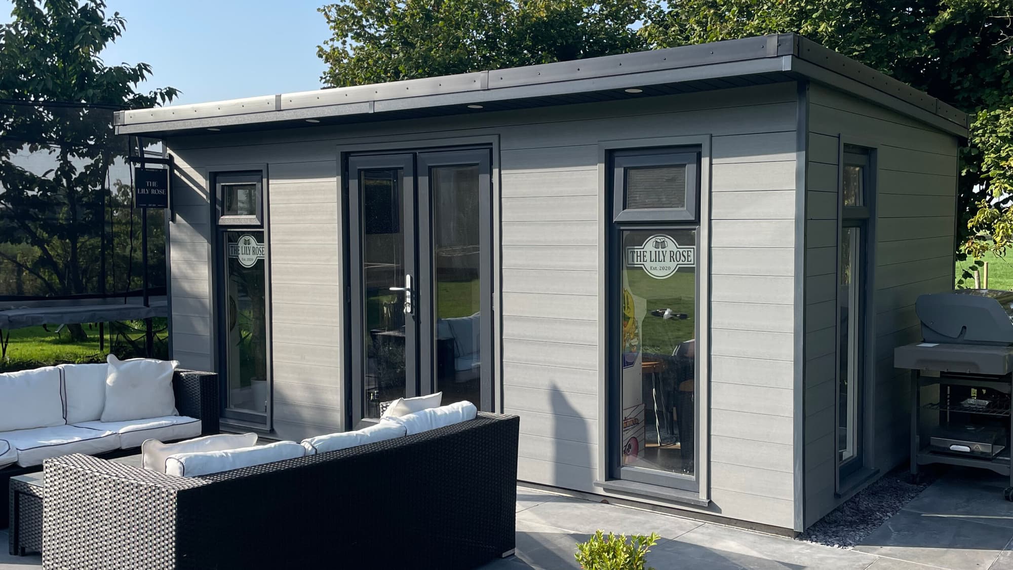 A modern pale grey composite garden room with outdoor rattan seating
