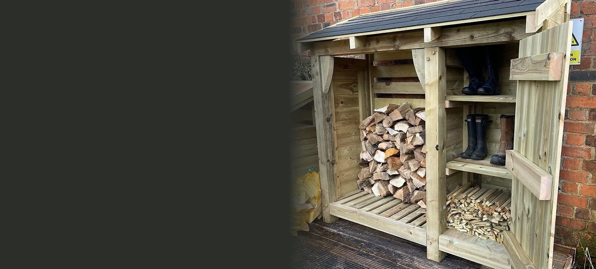 A timber log store with its door open, showing stacked logs, boots on a shelf and a store of kindling