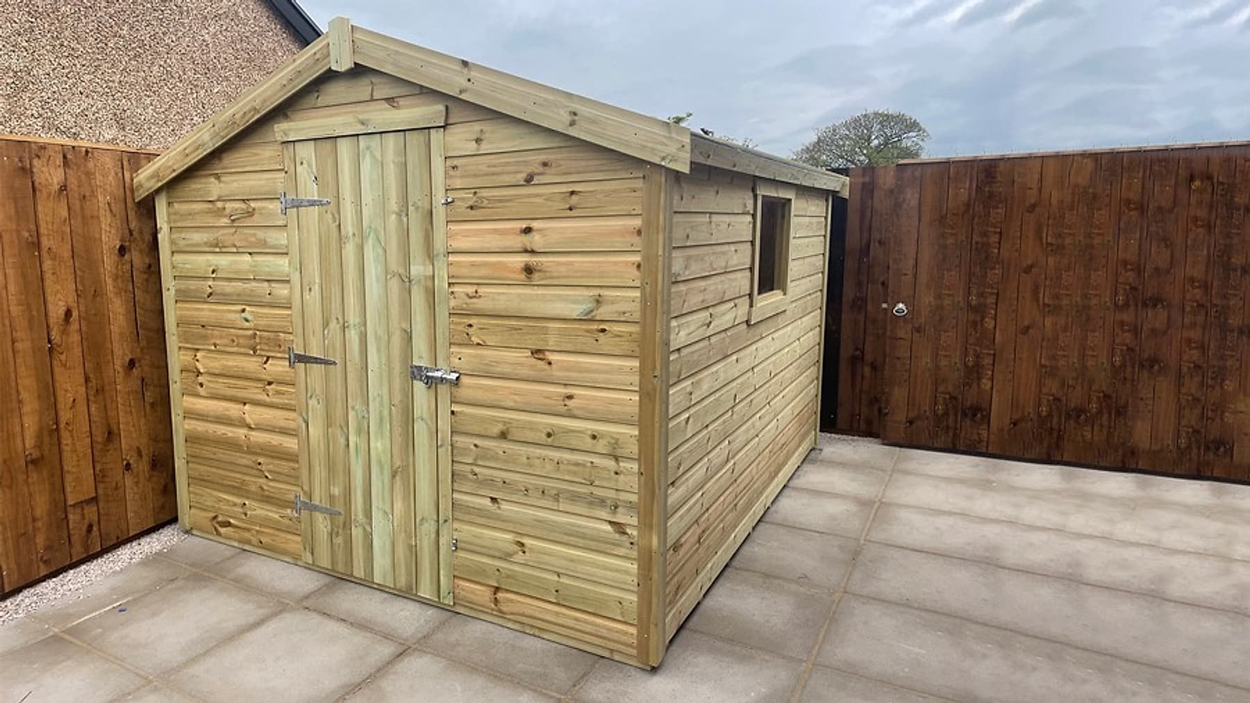 An apex timber shed with double doors on a clean paved yard