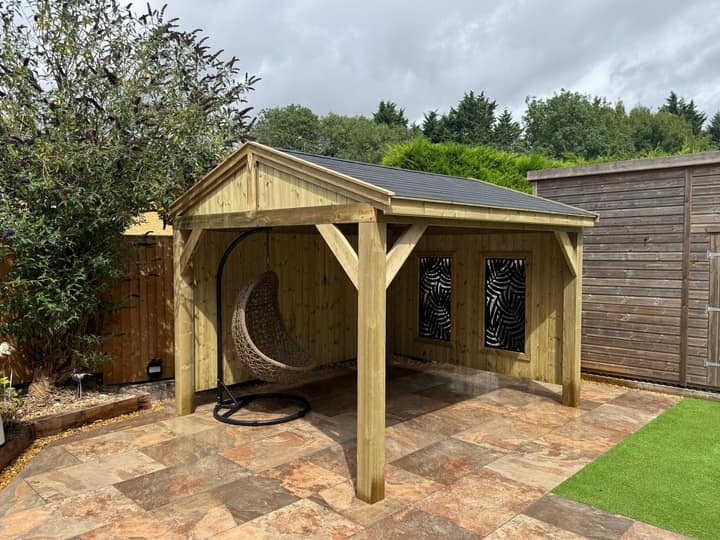 The Kensington gazebo with a gabled felt shingle roof, open sides and privacy panels, on a tiled patio