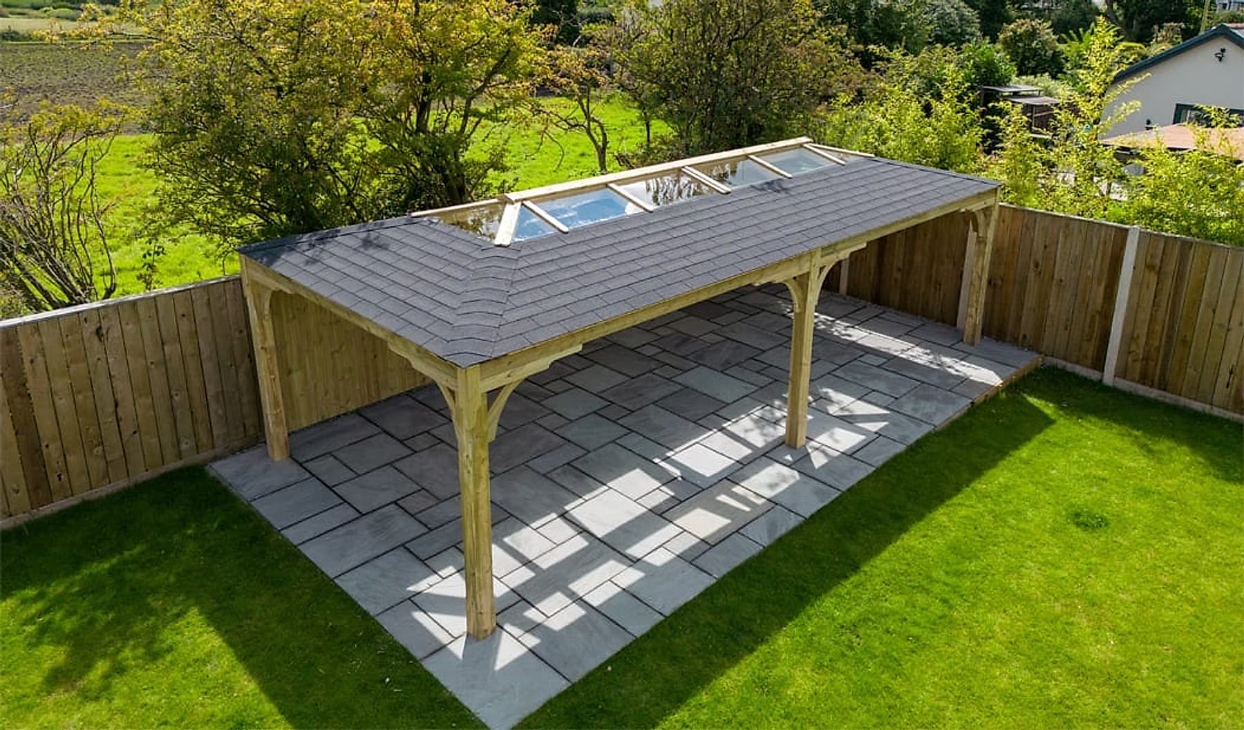 A timber gazebo with a glazed roof section on a paved patio